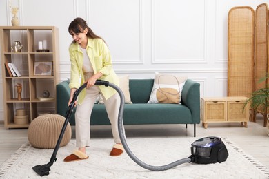 Young woman vacuuming carpet in living room