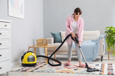 Young woman vacuuming carpet in living room