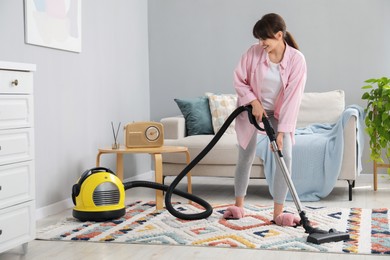 Young woman vacuuming carpet in living room