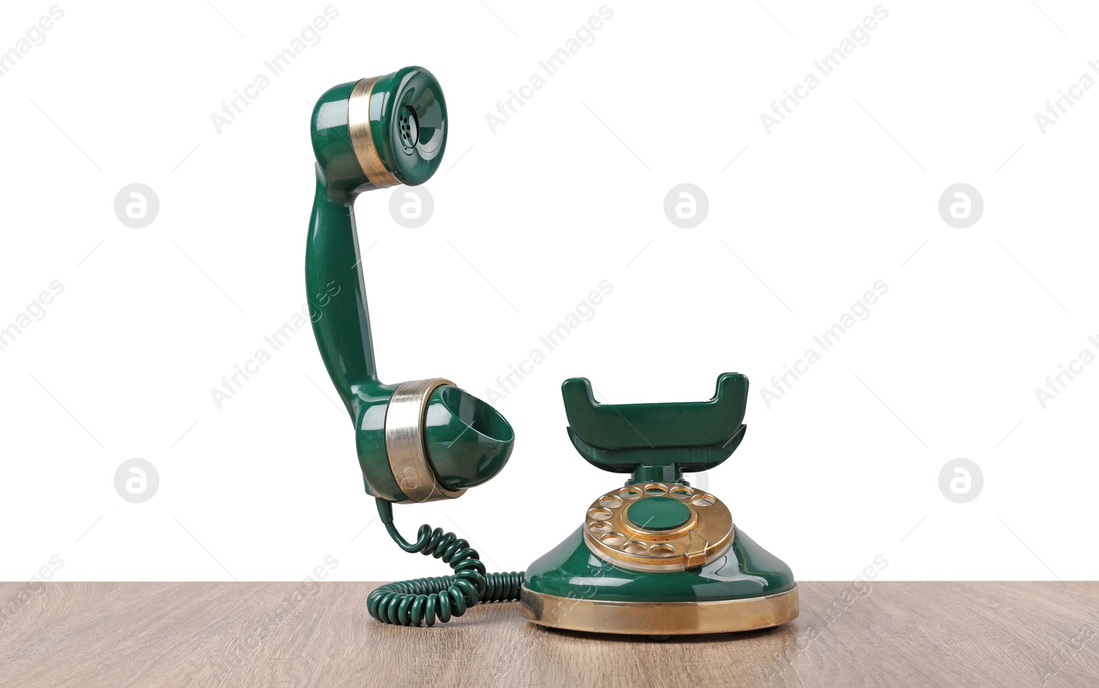 Photo of Green vintage corded telephone on wooden table against light background