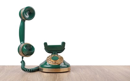 Photo of Green vintage corded telephone on wooden table against light background, space for text