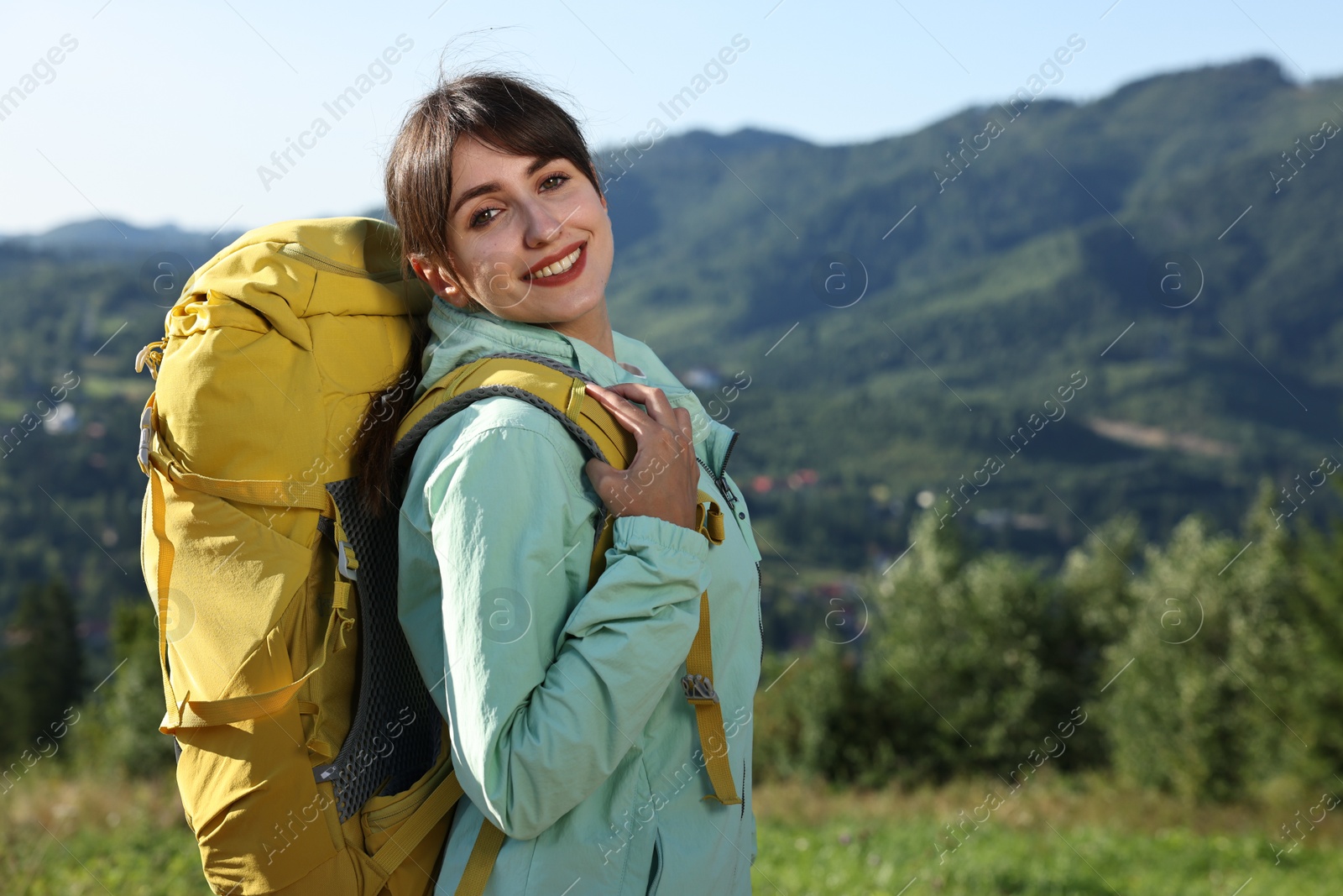 Photo of Smiling woman with backpack in beautiful mountains, space for text