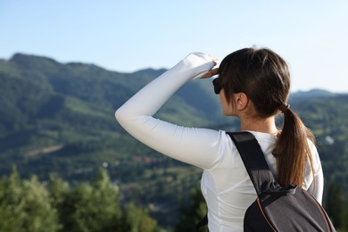 Young woman in sunglasses with backpack in beautiful mountains