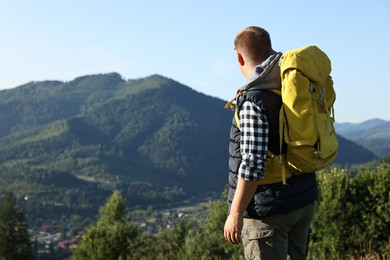 Man with backpack in beautiful mountains, space for text