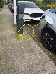 Modern electric car charging from station outdoors