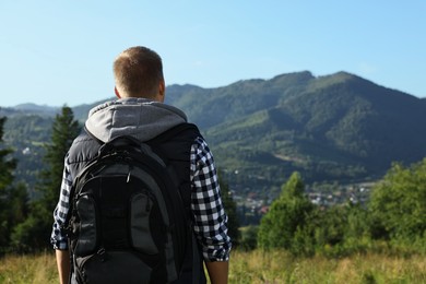 Photo of Man with backpack in beautiful mountains, back view. Space for text