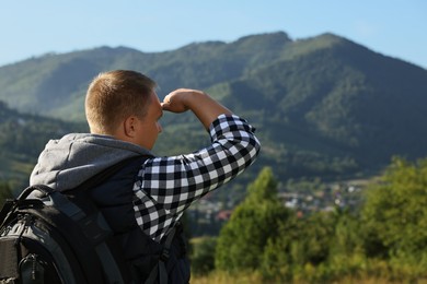 Photo of Man with backpack in beautiful mountains, back view. Space for text