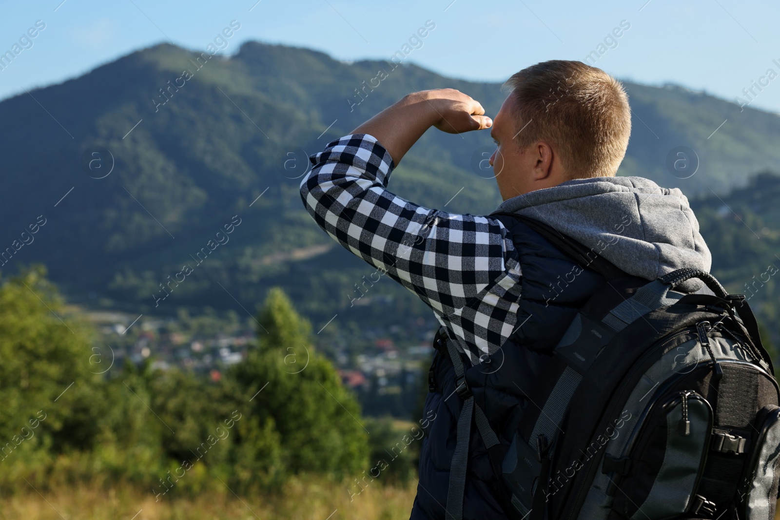 Photo of Man with backpack in beautiful mountains, back view. Space for text