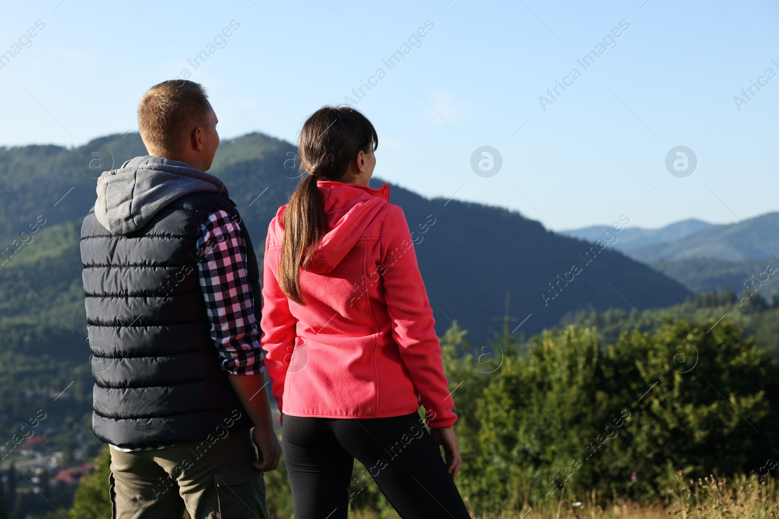 Photo of Couple in beautiful mountains, back view. Space for text