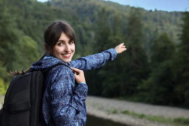 Smiling woman with backpack in beautiful mountains, space for text