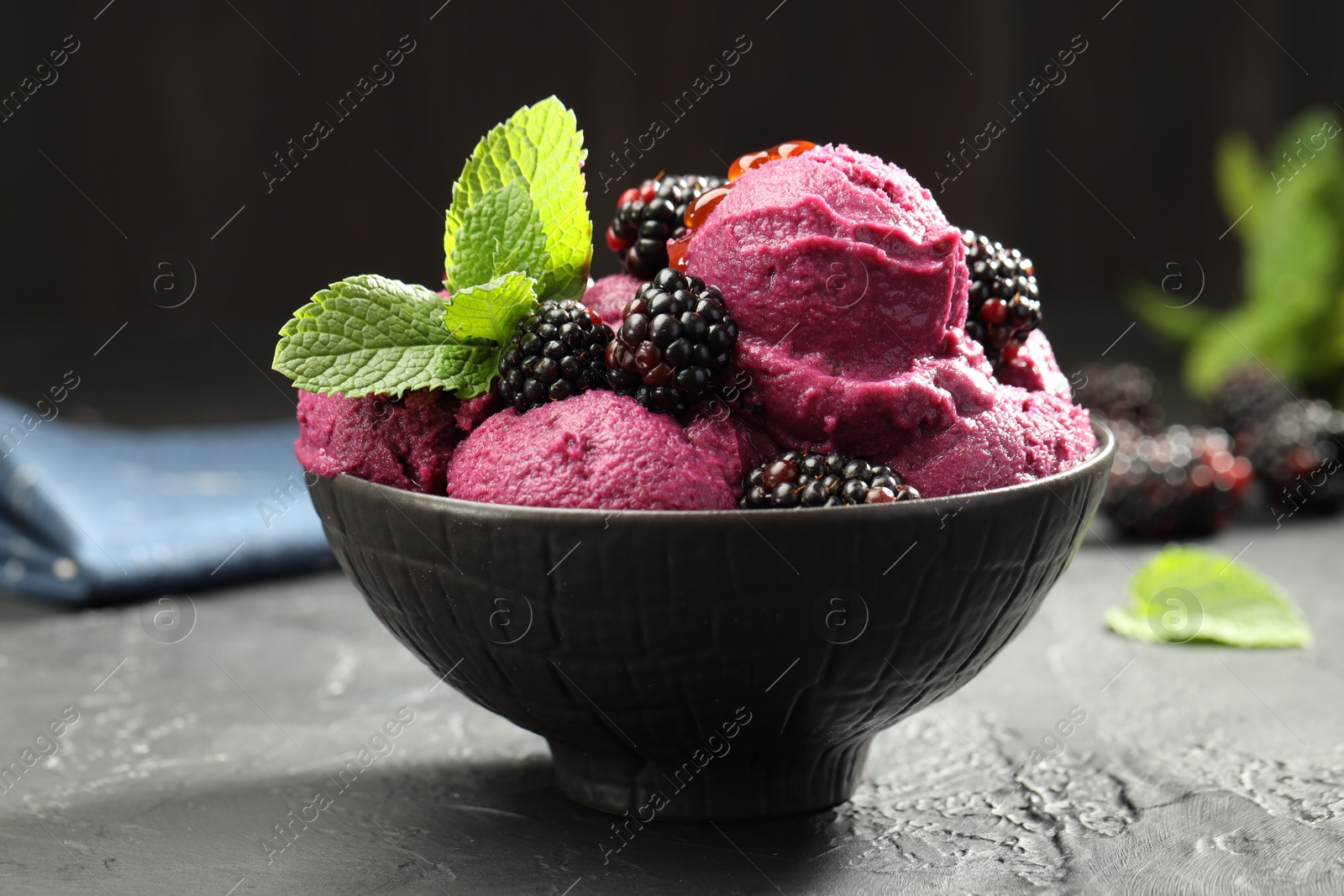 Photo of Delicious blackberry sorbet, fresh berries and mint in bowl on gray textured table