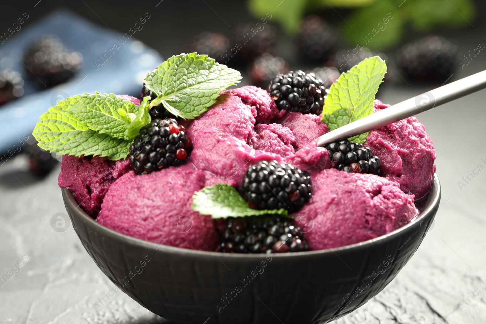 Photo of Delicious blackberry sorbet, fresh berries and mint in bowl served on gray textured table, closeup