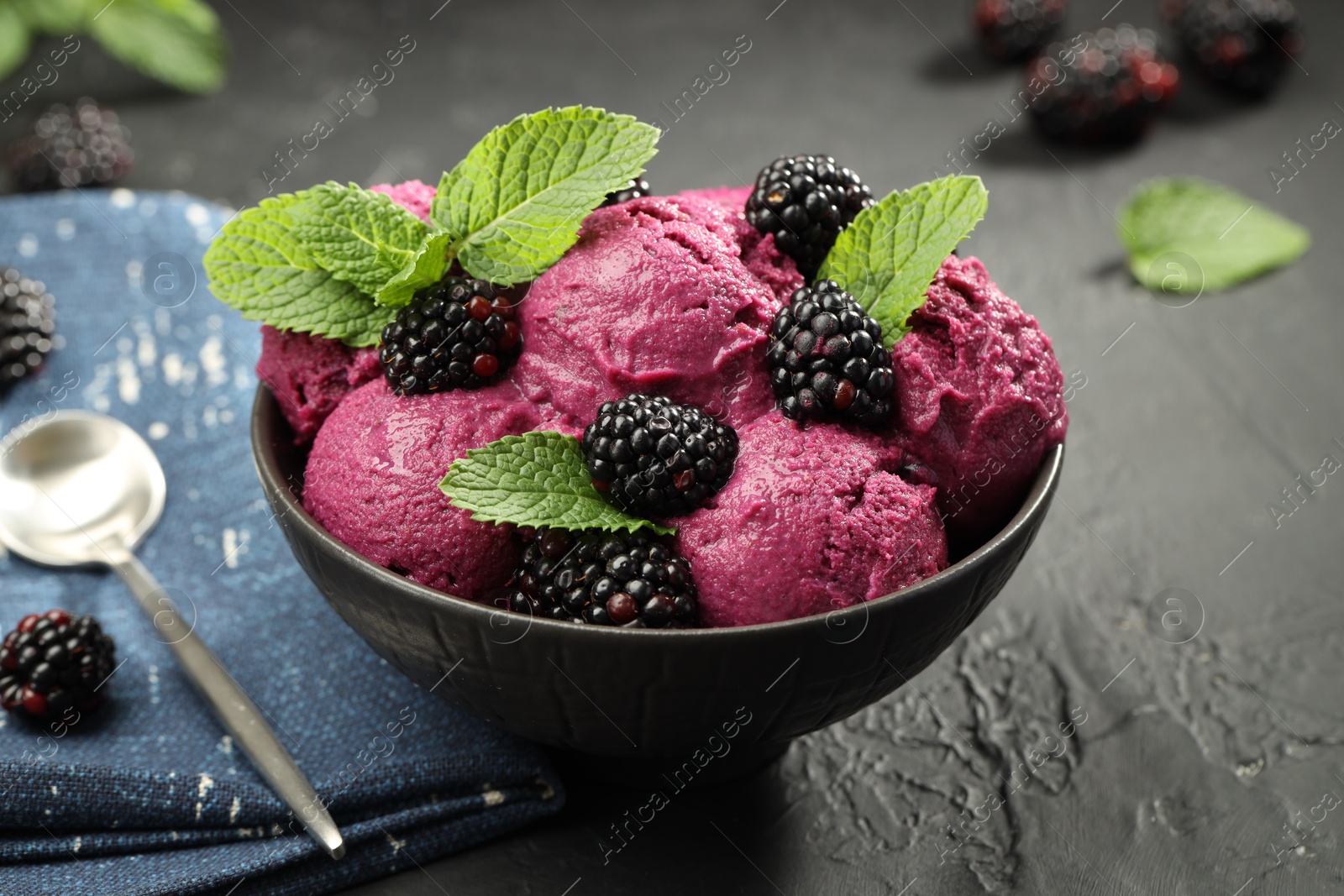 Photo of Delicious blackberry sorbet, fresh berries and mint in bowl served on gray textured table