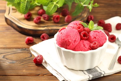 Photo of Delicious raspberry sorbet, fresh berries and mint in bowl on wooden table