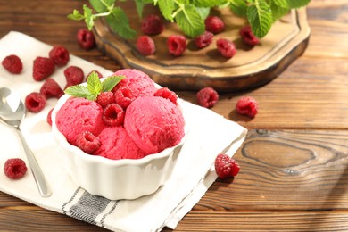 Photo of Delicious raspberry sorbet with fresh berries in bowl and spoon on wooden table