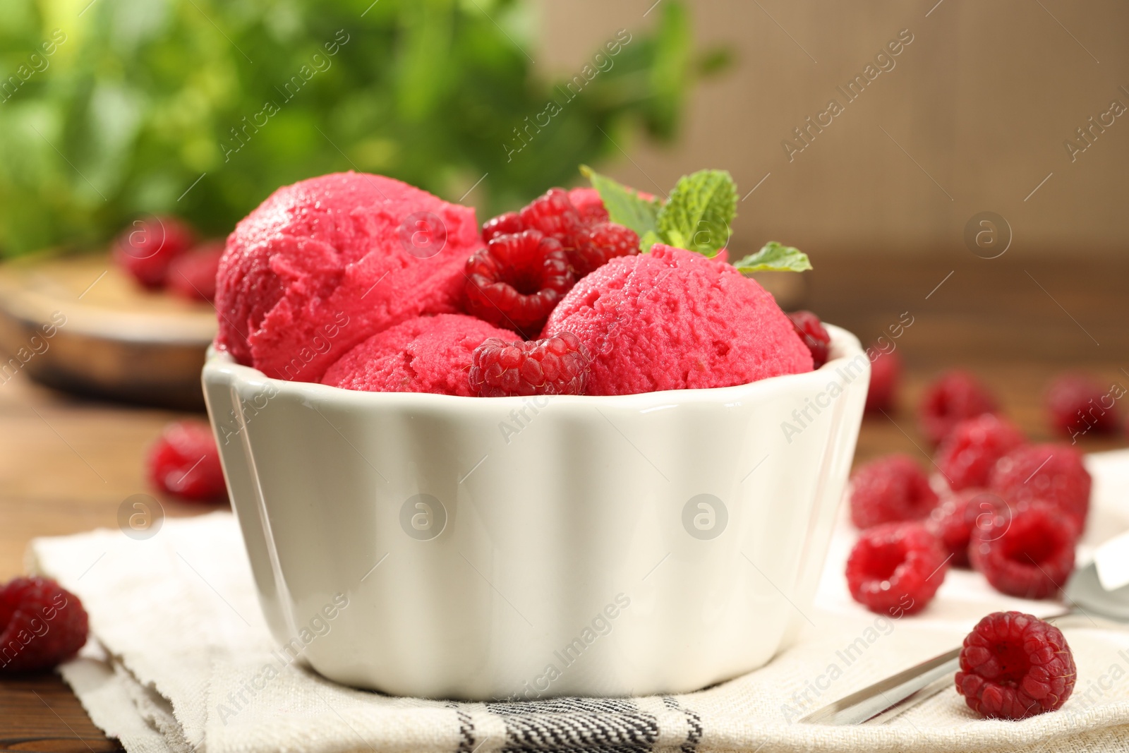 Photo of Delicious raspberry sorbet, fresh berries and mint in bowl on table, closeup