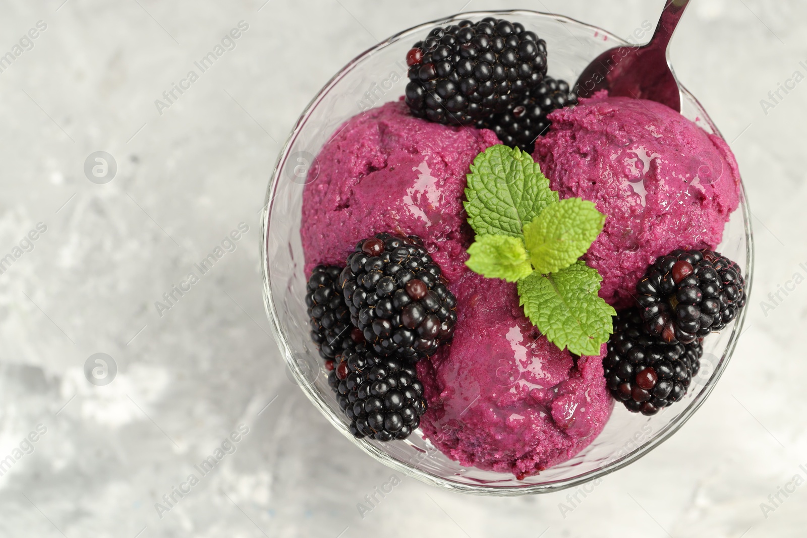 Photo of Delicious blackberry sorbet, fresh berries and mint in glass dessert bowl served on gray textured table, top view