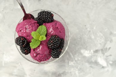 Photo of Delicious blackberry sorbet, fresh berries and mint in glass dessert bowl served on gray textured table, top view. Space for text