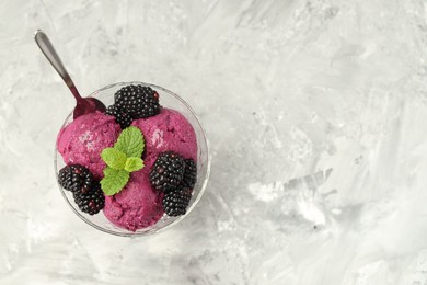 Photo of Delicious blackberry sorbet, fresh berries and mint in glass dessert bowl served on gray textured table, top view. Space for text