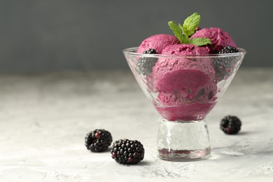 Photo of Delicious blackberry sorbet, fresh berries and mint in glass dessert bowl on gray textured table, space for text