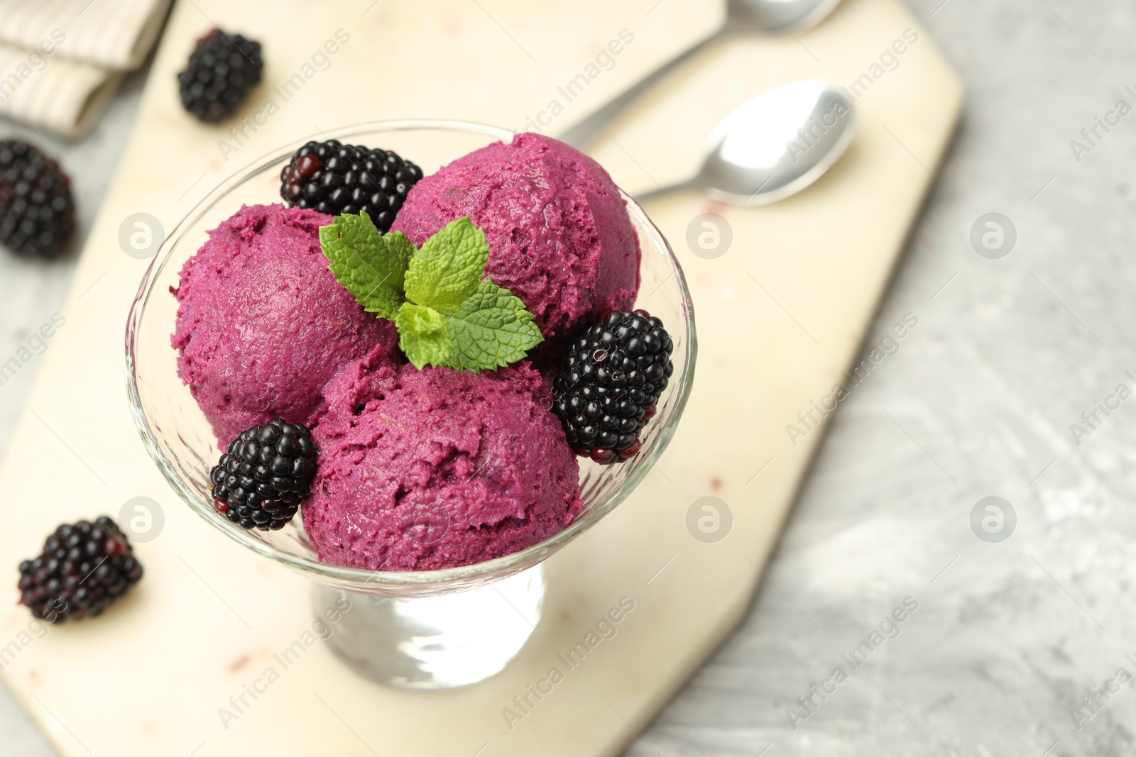 Photo of Delicious blackberry sorbet, fresh berries and mint in glass dessert bowl on gray textured table, closeup