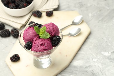 Delicious blackberry sorbet, fresh berries and mint in glass dessert bowl on gray textured table