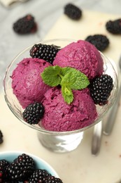 Photo of Delicious blackberry sorbet, fresh berries and mint in glass dessert bowl on table, closeup