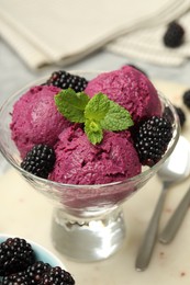 Photo of Delicious blackberry sorbet, fresh berries and mint in glass dessert bowl on table, closeup