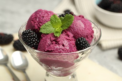 Photo of Delicious blackberry sorbet, fresh berries and mint in glass dessert bowl on table, closeup