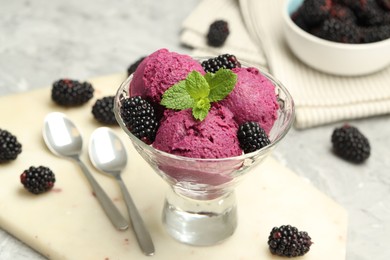 Delicious blackberry sorbet with fresh berries in bowl and spoons on gray table