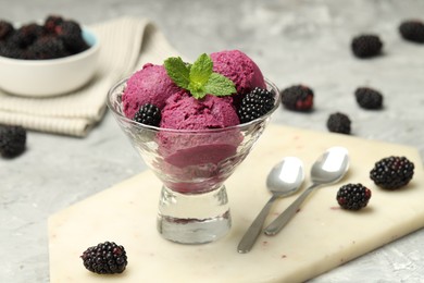 Photo of Delicious blackberry sorbet with fresh berries in bowl and spoons on gray textured table