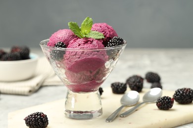 Photo of Delicious blackberry sorbet with fresh berries in bowl and spoons on gray table