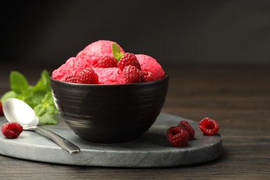 Delicious raspberry sorbet with fresh berries in bowl and spoon on wooden table