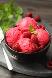 Photo of Delicious raspberry sorbet with fresh berries in bowl and spoon on table, closeup