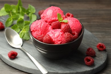 Photo of Delicious raspberry sorbet in bowl, fresh berries, mint and spoon on wooden table, closeup