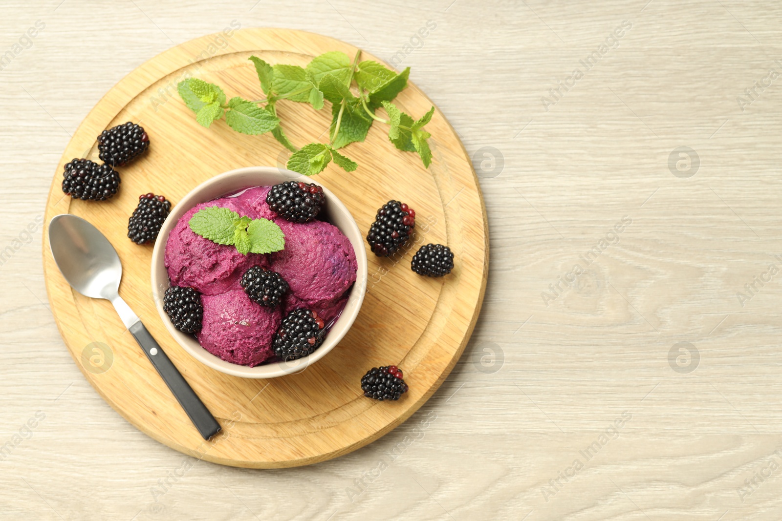 Photo of Delicious blackberry sorbet with fresh berries in bowl and spoon on table, top view. Space for text