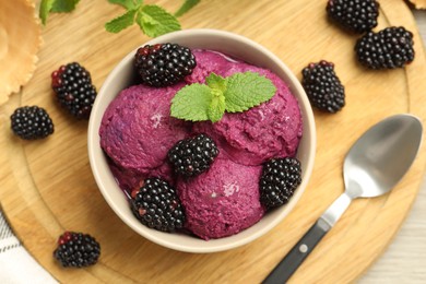 Photo of Delicious blackberry sorbet with fresh berries in bowl and spoon on table, top view