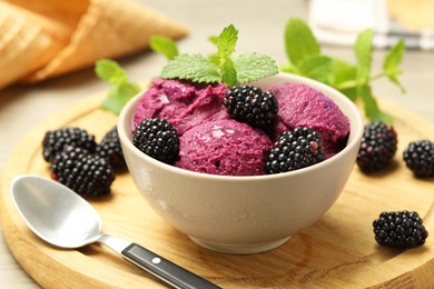 Photo of Delicious blackberry sorbet with fresh berries in bowl and spoon on table, closeup