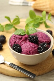 Photo of Delicious blackberry sorbet with fresh berries in bowl and spoon on table