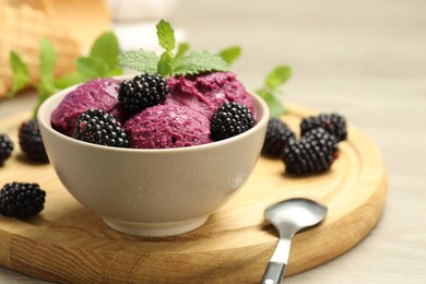 Delicious blackberry sorbet with fresh berries in bowl and spoon on table, closeup