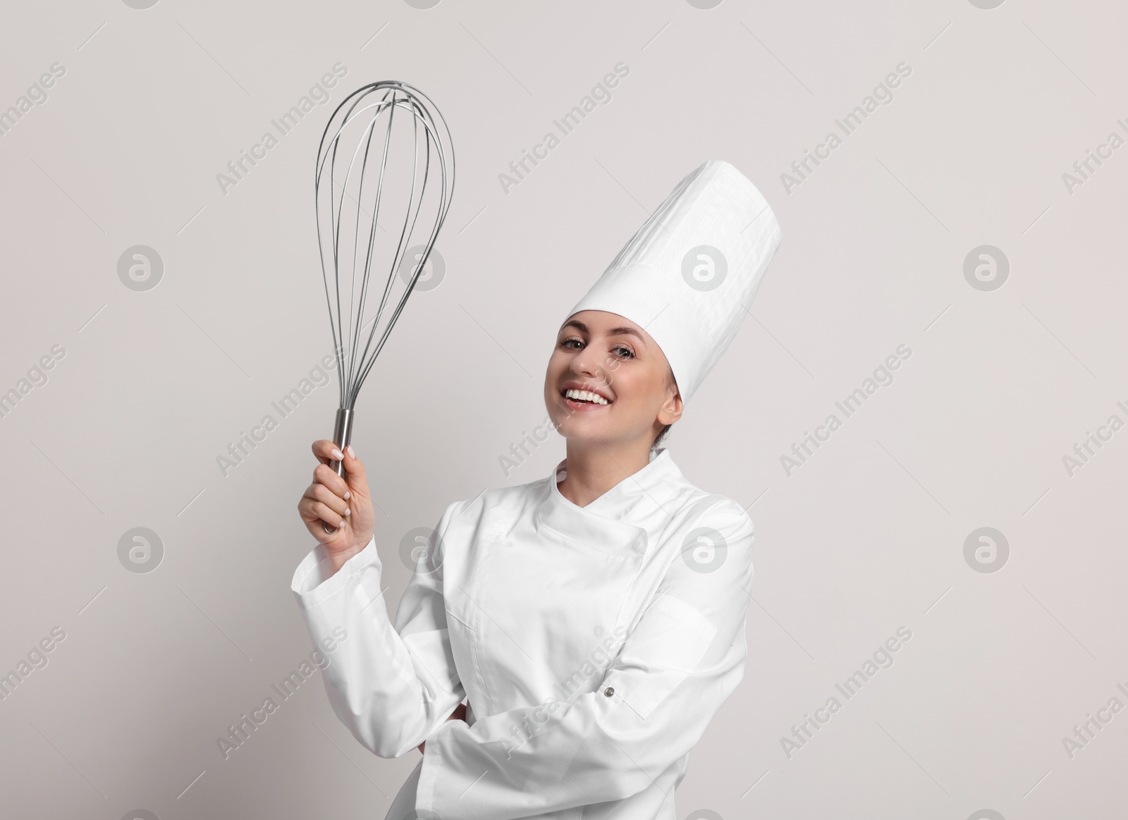 Image of Happy pastry chef with big whisk on light grey background