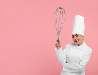 Happy pastry chef with big whisk on pink background. Space for text