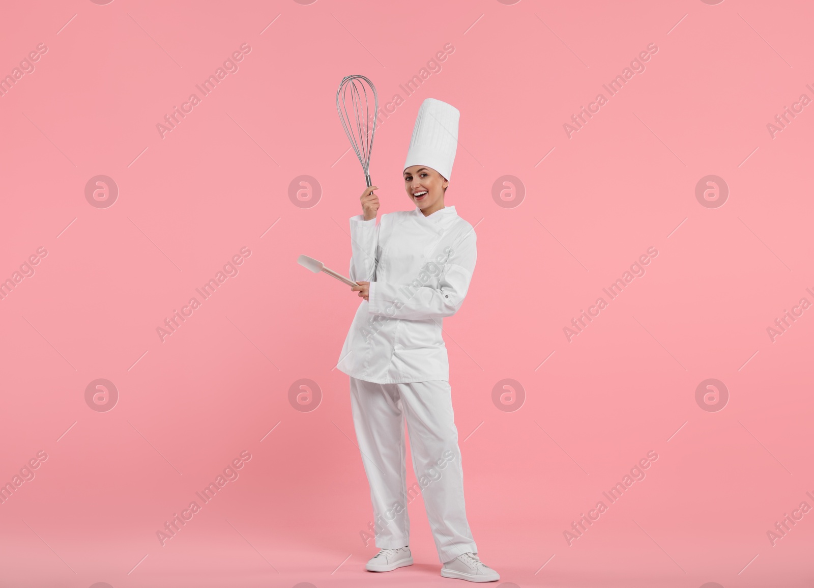 Image of Happy pastry chef with big whisk and spatula on pink background