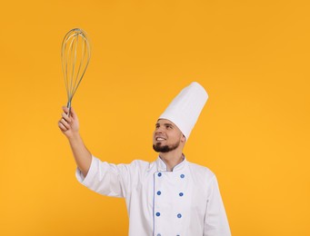 Happy pastry chef with big whisk on orange background