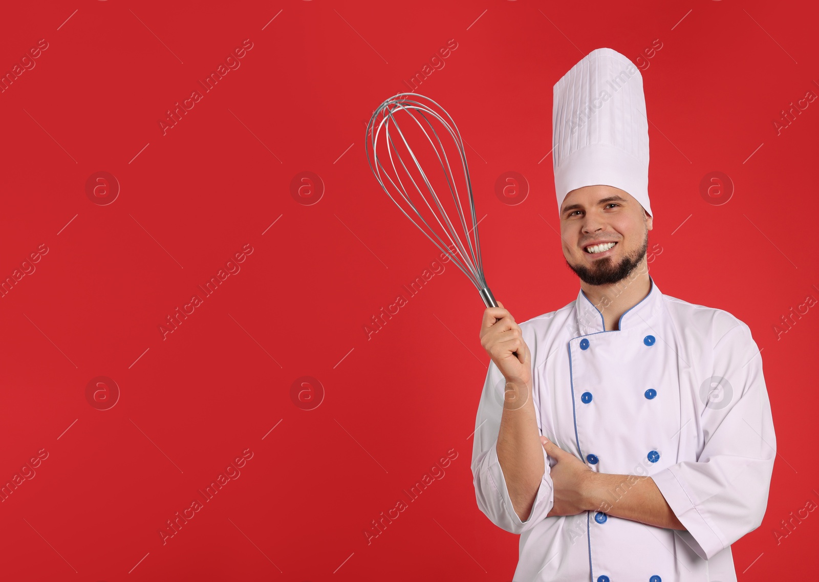 Image of Happy pastry chef with big whisk on red background. Space for text