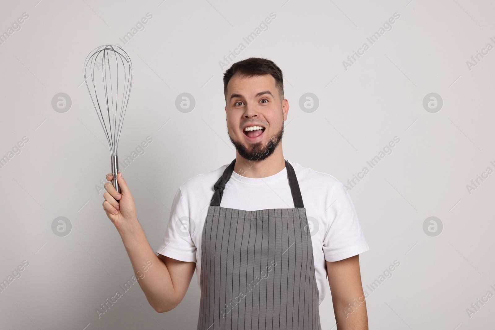 Image of Emotional pastry chef with big whisk on light grey background