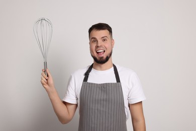 Image of Emotional pastry chef with big whisk on light grey background