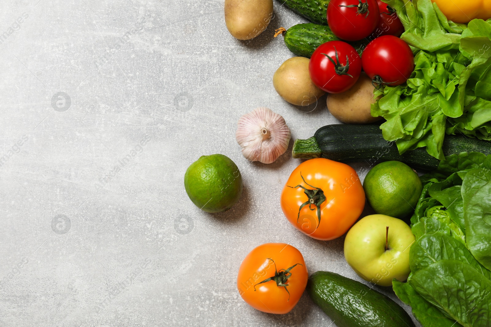 Photo of Healthy vegetarian food. Different vegetables, apple and lime on grey textured table, flat lay. Space for text