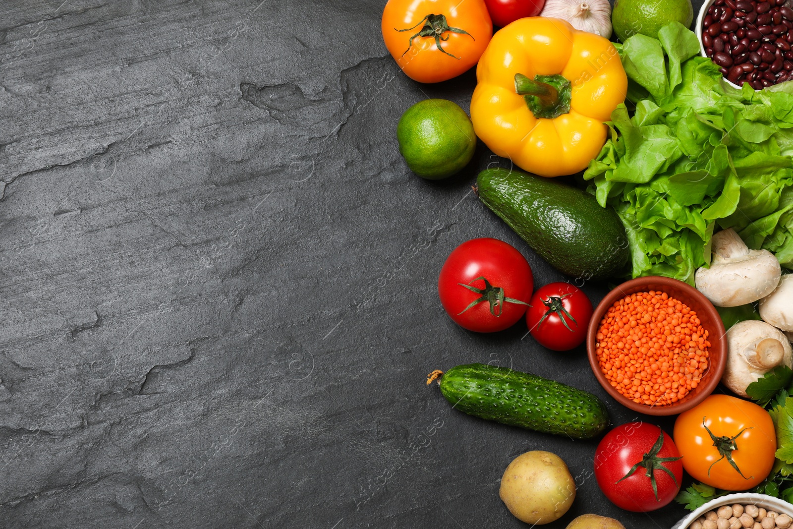 Photo of Healthy vegetarian food. Different vegetables, lentils and lime on dark textured table, flat lay. Space for text