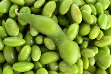 Raw green edamame pod on soybeans as background, top view